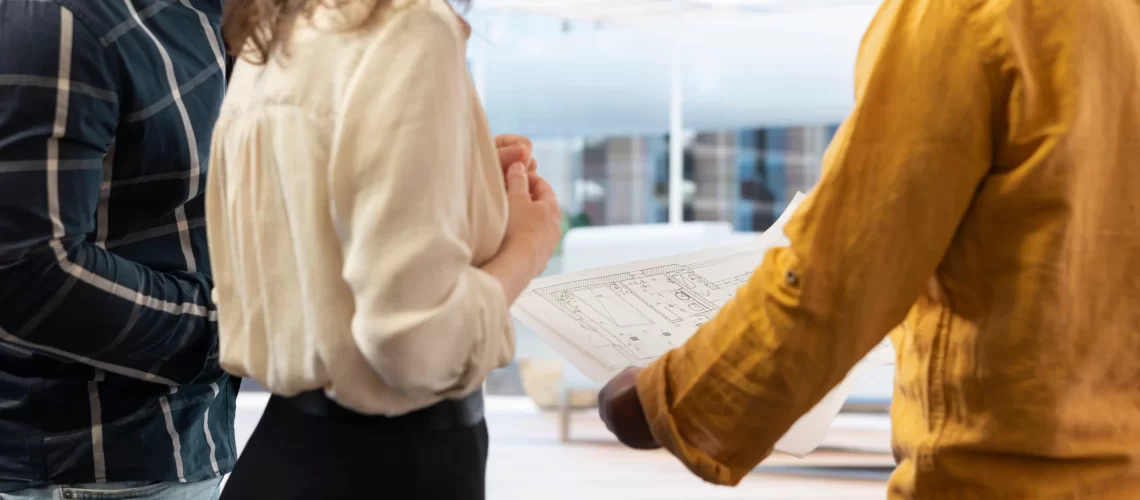 real-estate-agent-guiding-clients-office-hunt-with-layout-blueprints